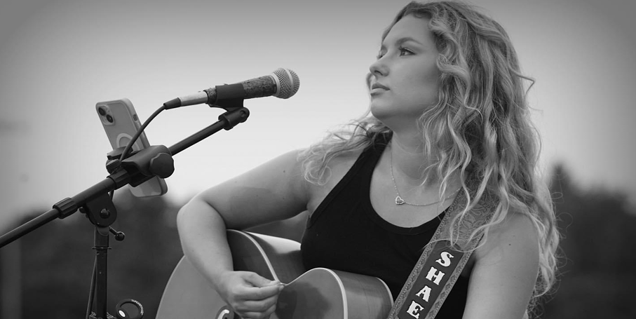An acoustic performer singing and playing guitar at the speedway