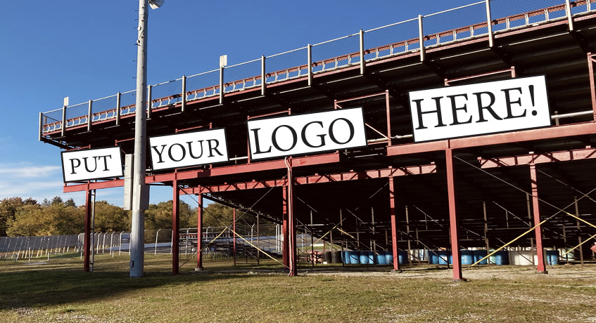 A row of blank white banners reading PUT YOUR LOGO HERE across the front of the grandstands