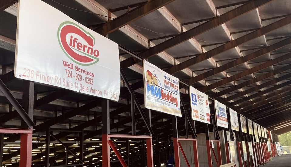 Sponsor signs hanging from the rafters of the midway under the grandstands